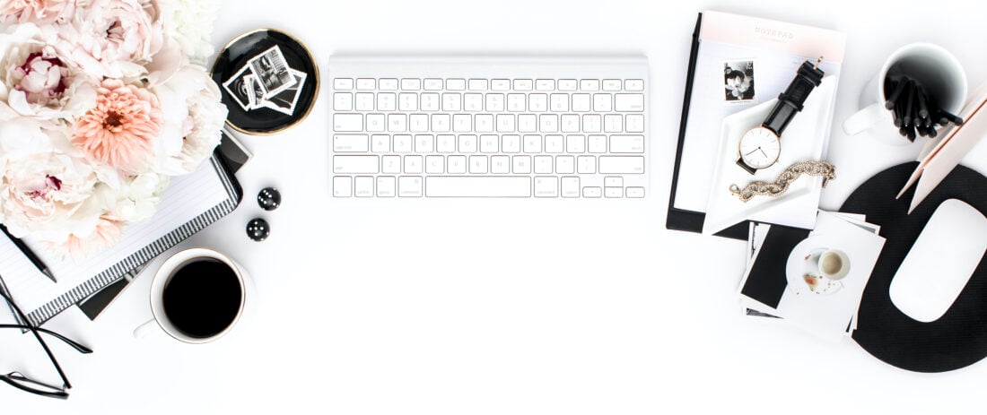 Computer keyboard, flowers, and glasses on a white desk