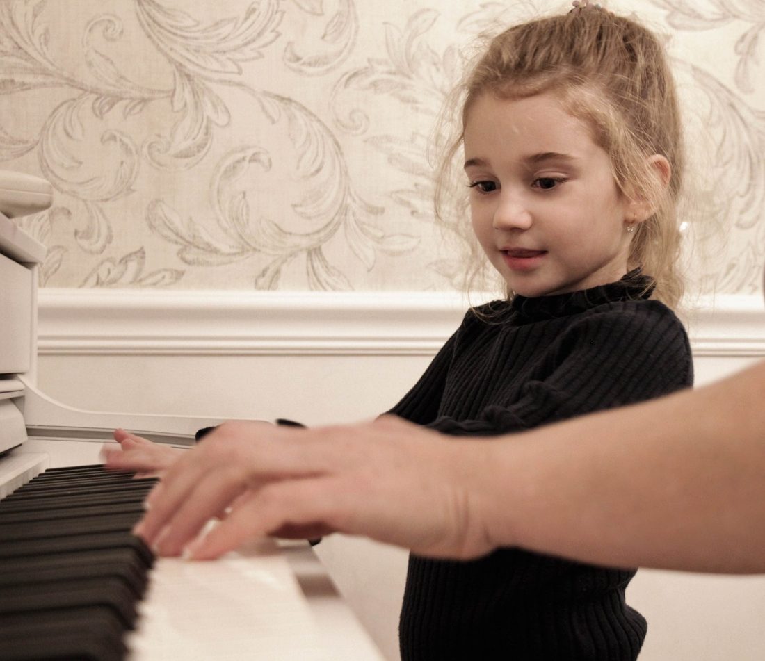Little girl playing piano for Advantages of Using Games to Teach Piano Improv
